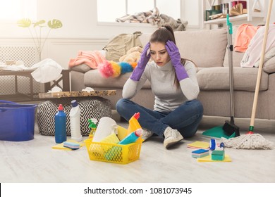 Shocked Woman Cleaning House With Lots Of Tools. Young Tired Girl Surprised Of Detergents Quantity, Copy Space