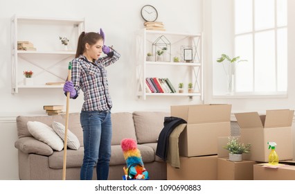 Shocked Woman Cleaning House With Lots Of Tools. Young Tired Girl Surprised Of Detergents Quantity And Mess, Copy Space