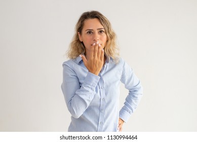 Shocked Woman Covering Mouth With Hand And Looking At Camera. Amazed Attractive Young Woman With Curly Hair Not Speaking. Surprised Concept