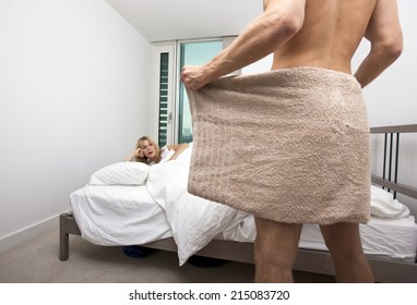 Shocked Woman Looking At Nude Man Holding Towel In Bedroom