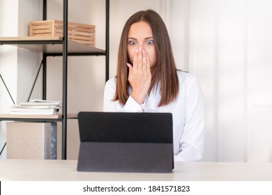 Shocked Woman. Online Conference. Bad News. Digital Technology. Scared Lady Looking At Tablet Computer Closing Mouth Hand Light Home Office Interior Background.