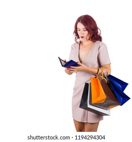  Shocked Woman Shopaholic Carrying Bags Holding A Empty Wallet, Has No Money For Shopping In Her Pouch Isolated Over White Background.