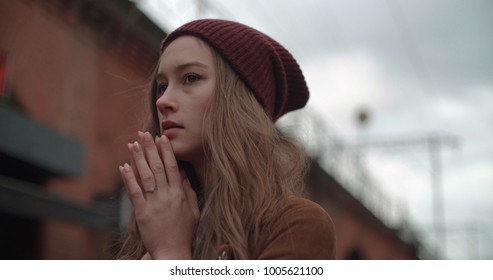 Shocked woman standing in a city street. Confused student girl covering her mouth by hands.