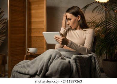 Shocked woman uses a digital tablet at home, watching movies online or surfing the Internet. - Powered by Shutterstock