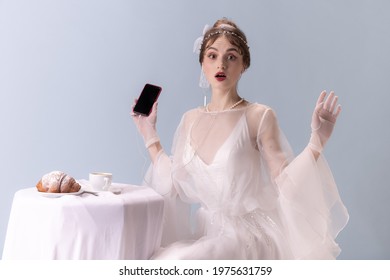 Shocked, wondered. Young woman in art action isolated on white background. Retro style, comparison of eras concept. Beautiful female model like princess, queen or duchess, old-fashioned tender outfit.
