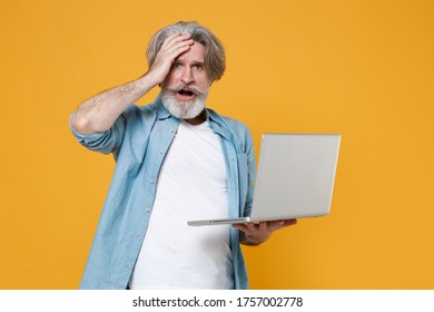 Shocked worried elderly gray-haired mustache bearded man in casual blue shirt isolated on yellow background. People lifestyle concept. Mock up copy space. Working on laptop computer put hand on head - Shutterstock ID 1757002778