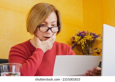 Shocked Worried Mature Woman Reading Paper Document Or Postal Letter Feeling Frustrated By Unexpected News Sitting At Home Indoor. Received Bank Account Balance Or Bad Notice, Fine, Bankruptcy