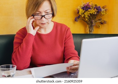 Shocked Worried Mature Woman Reading Paper Document Or Postal Letter Feeling Frustrated By Unexpected News Sitting At Home Indoor. Received Bank Account Balance Or Bad Notice, Fine, Bankruptcy