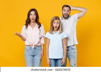 Shocked Worried Young Parents Mom Dad With Child Kid Daughter Teen Girl In Basic T-shirts Put Palm On Head Spreading Hands Isolated On Yellow Background Studio Portrait. Family Day Parenthood Concept