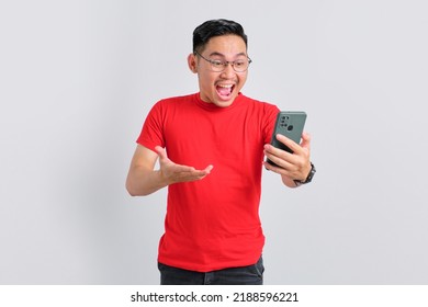 Shocked Young Asian Man Looking At Mobile Phone Screen Reacting To Online News With Opened Mouth Isolated Over White Background