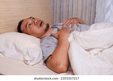 Shocked young Asian man waking up in despair after nightmare. - Shutterstock ID 2355357217