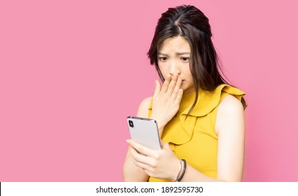 Shocked young asian woman watching a smart phone.