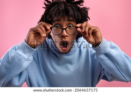 Shocked young black teen guy opening mouth in awe, touching eyeglasses, looking at camera on pink studio background. Emotional African American teenager screaming OMG, feeling surprised Foto stock © 