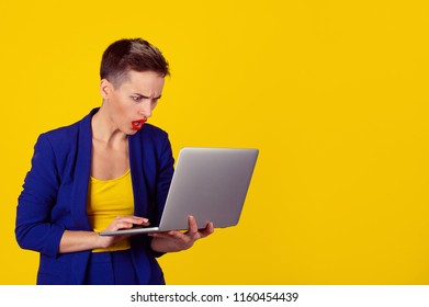 Shocked Young Business Woman Using Laptop Looking At Computer Screen Blown Away In Stupor Isolated On Yellow Background. Human Face Expression, Emotion, Feeling, Perception, Body Language, Reaction.