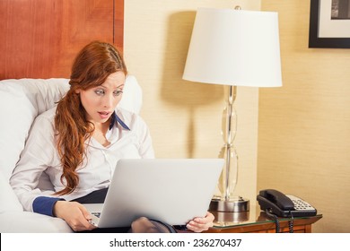 Shocked Young Business Woman Using Laptop Looking At Computer Screen Blown Away In Stupor Sitting In Bed At Home, Hotel. Human Face Expression, Emotion, Feeling, Perception, Body Language, Reaction