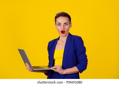 Shocked Young Business Woman Using Laptop Looking At You Camera Blown Away In Stupor Standing On A Yellow Background. Human Face Expression, Emotion, Feeling, Perception, Body Language, Reaction