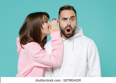 Shocked young couple two friends man woman 20s wearing white pink casual hoodie standing whispering secret behind hand, sharing news isolated on blue turquoise colour wall background studio portrait - Powered by Shutterstock