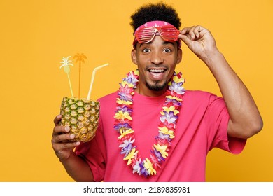 Shocked Young Fun Man He Wear Pink T-shirt Hawaiian Lei Near Hotel Pool Drink Straw Pineapple Juice Take Off Glasses Look Camera Isolated On Plain Yellow Background. Summer Vacation Sea Rest Concept