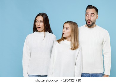 Shocked Young Happy Parents Mom Dad With Child Kid Daughter Teen Girl In Basic White Sweaters Looking Aside Isolated On Blue Color Background Studio Portrait. Family Day Parenthood Childhood Concept