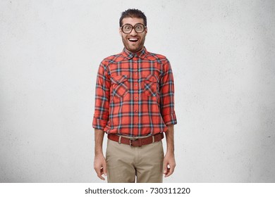 Shocked Young Male Nerd Wears Old Fashionable Glasses Checkered Shirt And Trousers Stares At Camera Shocked Young Male Nerd Wears Old Fashionable Glasses Checkered Shirt And Trousers Stares At Camera