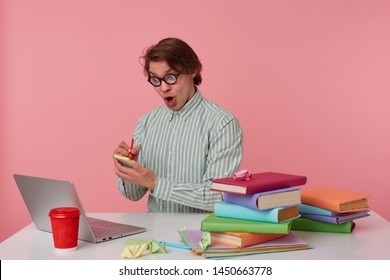 Shocked Young Man In Glasses Sits By The Table And Working With Laptop, Writes The Solution Of The Equation On The Stickers Isolated Over Pink Background.