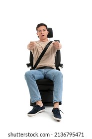 Shocked young man with imaginary steering wheel in car seat on white background