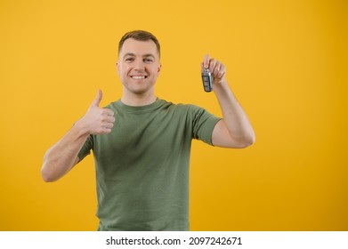 Shocked Young Man Posing Isolated On Yellow Orange Background, Studio Portrait. People Emotions Lifestyle Concept. Mock Up Copy Space. Holding In Hand Car Keys, Showing Thumb Up