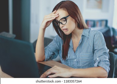 Shocked young redhead woman looking at laptop computer screen at home surprised by email notification message reading bad news online about debt, unexpected rejection, having financial problem - Shutterstock ID 1183357264