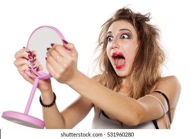 Shocked Young Woman With Bad Makeup And Messy Hair Looking At Herself In The Mirror