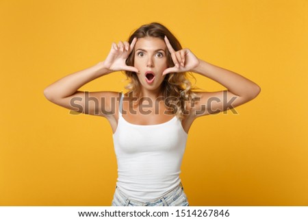 Shocked young woman girl in light casual clothes posing isolated on yellow orange wall background studio portrait. People lifestyle concept. Mock up copy space. Keeping mouth open, stretching eyelids