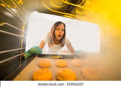 Shocked Young Woman Looking At Burnt Cookies In Oven