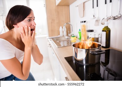 Shocked Young Woman Looking At Burnt Food In Cooking Pot