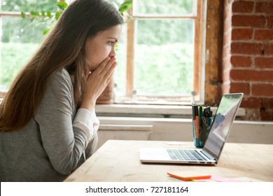 Shocked young woman looking at laptop screen at work desk. Casual business lady in office seeing something unbelievable on computer. Bad news concept, dismissal notice from boss, work-related mistake.