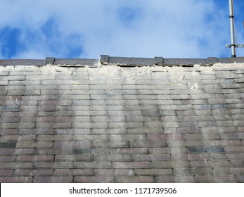 Shoddy Roofing Work By Cowboy Builder. Results Of Rogue Worker Posing As Skilled Tradesman. Badly Pointed Ridge Tiles On Slate Roof, Mortar Running Down Tiles. Close Up.