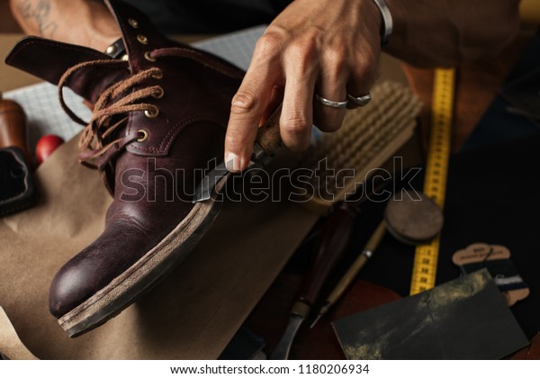 Shoe or belt maker working\
place at leather workshop with cobbler s and craft tools on\
background