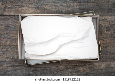 Shoe box with white paper on wooden background, top view. Shoebox, flat lay