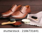 Shoe care products and footwear on wooden table, closeup