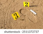 Shoe print in sand, firearm shell casing with scale ruler and number plate, evidence, crime scene examination, forensic examination of traces