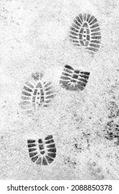 Shoe Prints On A Background Of Gray Snow. Shoe Tread Marks On The Snow-covered Surface.