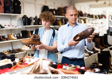 Shoe Salesman Helping Teen To Choose Fashionable Winter Boots At Shoe Store