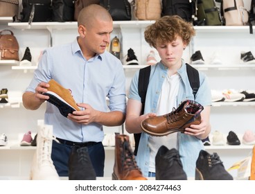 Shoe Salesman Helping Teen To Choose Fashionable Winter Boots At Shoe Store