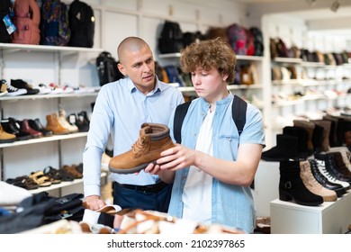 Shoe Salesman Helping Teen To Choose Fashionable Winter Boots At Shoe Store