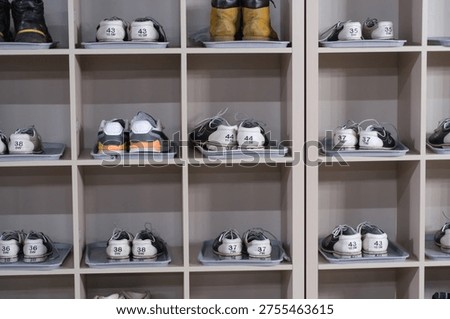 Shoe storage unit features multiple pairs of athletic shoes and boots, each with numbered labels for organization and easy identification