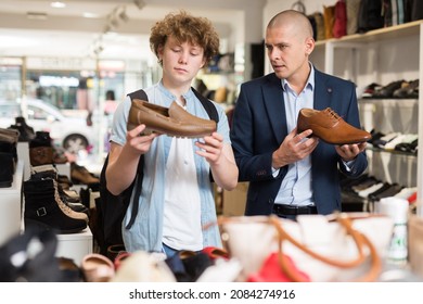 Shoe Store Employee Helping Teen To Choose Classic Brown Shoes In A Shoe Store