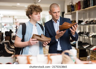 Shoe store employee helping teen to choose classic brown shoes in a shoe store - Shutterstock ID 2175313865