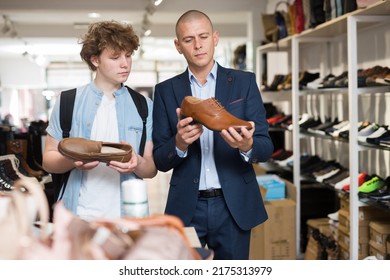 Shoe Store Employee Helping Teen To Choose Classic Brown Shoes In A Shoe Store