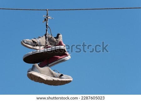 Shoe throwing tradition old shoes hanging on wires. Sneakers hanging on electric wires against a background of blue sky. Old shoes hanging on a wire
