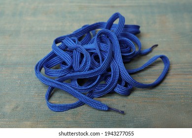 Shoelaces on light blue wooden background. Stylish accessory