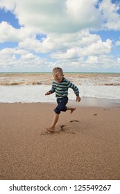 Shoeless happy little boy running at the sea coast - Shutterstock ID 125549267