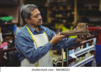 Shoemaker examining a shoe in workshop - Powered by Shutterstock